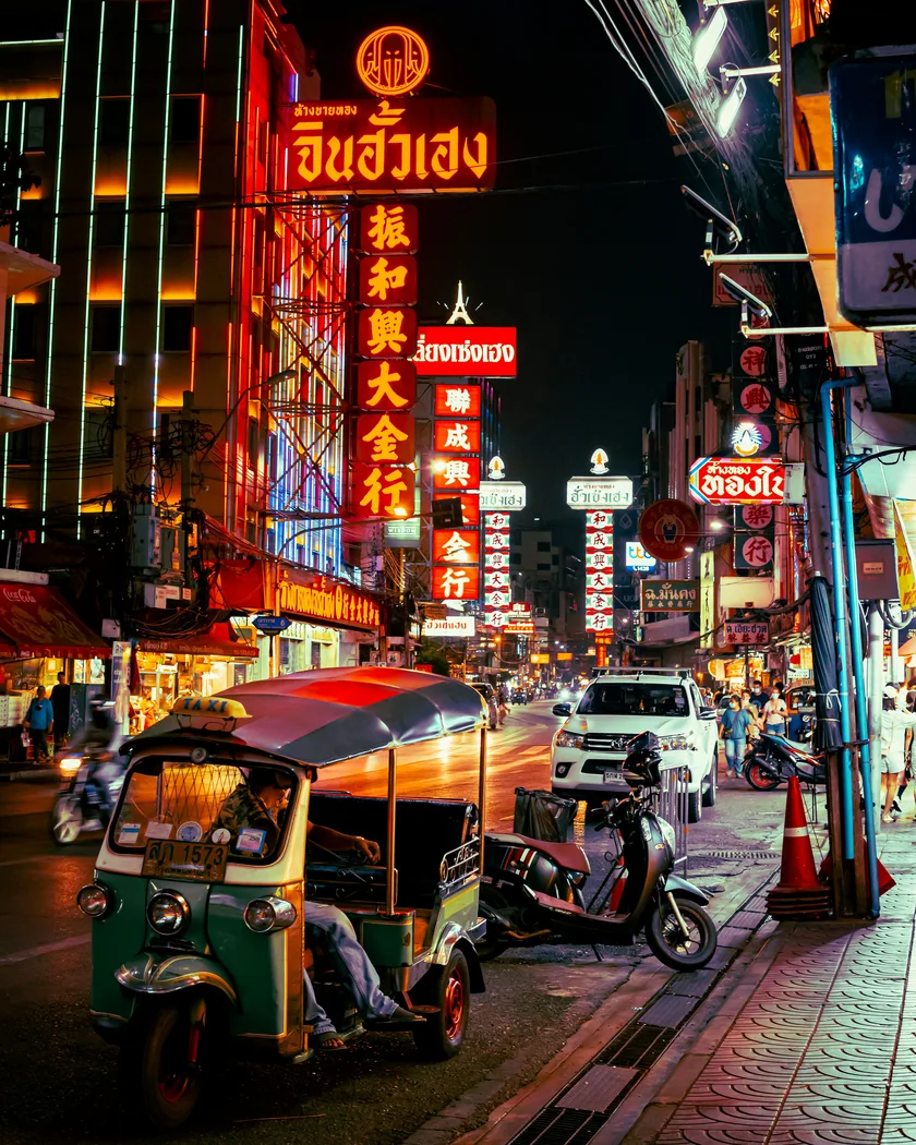 Bangkok Chinatown street at night with neon signs and scooters