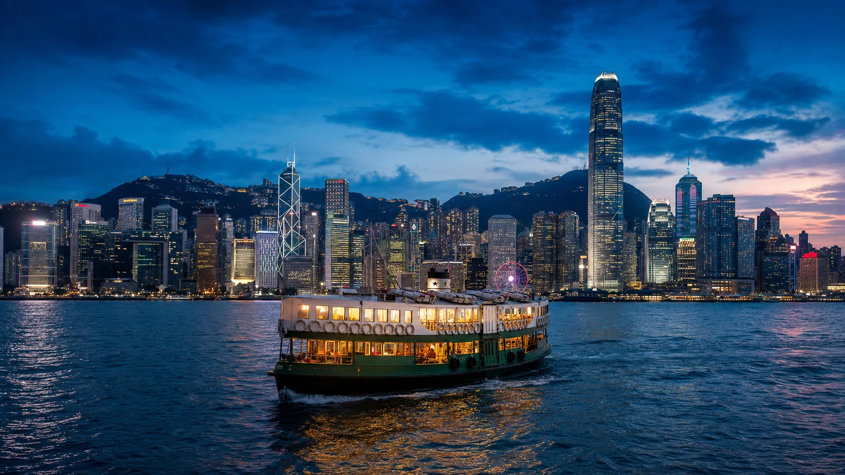 Star Ferry crossing Victoria Harbour at blue hour with the Hong Kong skyline behind it